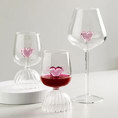 three wine glasses with hearts on them sitting on a white countertop next to each other