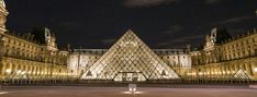 the pyramid shaped building is lit up at night