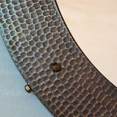 a close up of a metal object with holes in the middle on a blue surface