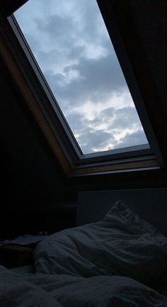 the sky is very cloudy in this room with a bed and pillows on it's side