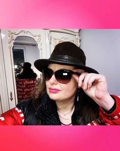 a woman wearing a hat and sunglasses in front of a mirror