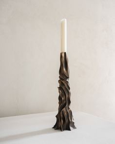 a tall candle holder with a white candle in it