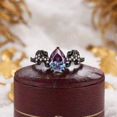 a ring with an amethorate and blue topaze on it sitting in a wooden box