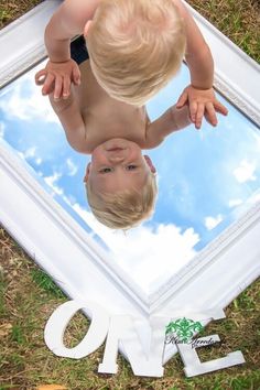 two toddlers looking at themselves in a mirror with the reflection of one on it