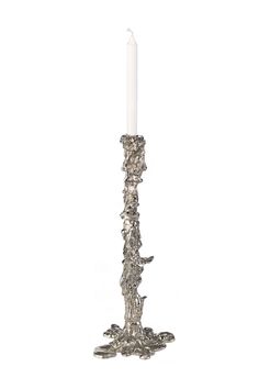 a tall metal candle holder with a white candle in it's center and silver leaves on the base