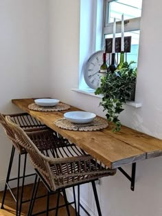 a wooden table topped with plates and bowls next to a window