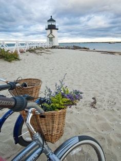 a bicycle parked on the beach next to a light house