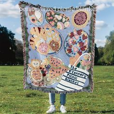 a person standing in the grass holding up a quilt