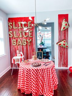 a red and white checkered table cloth on a wooden floor in front of a party backdrop