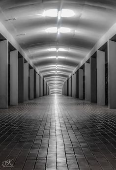 an empty hallway with white walls and tile flooring in black and white photograph by steve garvin