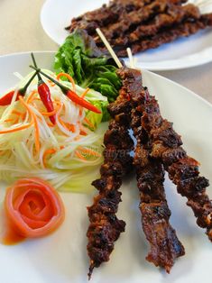 two white plates topped with meat and veggies