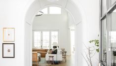 an archway leads into a living room with white walls and wood flooring, along with pictures on the wall