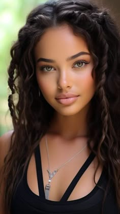 a beautiful young woman with long curly hair wearing a black tank top and silver necklace