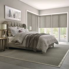 a large bed sitting in a bedroom next to a window with roller shades on it