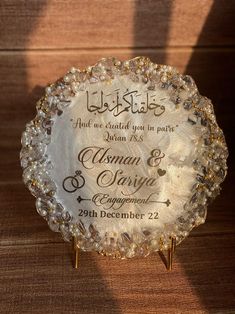 a glass plaque with the names of two people in arabic and english on it, sitting on a wooden surface