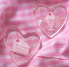 two heart shaped glass dishes sitting on top of a pink checkered table cloth