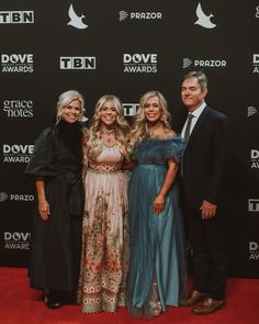 three women and two men standing on a red carpet