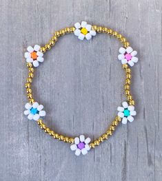 Flower Beaded Bracelet - multi color with 3mm 18k gold filled beads ✨✨ Bracelet comes as shown, if you would like another color please add in Personalization Section* CARING TIPS FOR YOUR JEWELRY ⭐️Treat and store with care. ⭐️ For longevity, avoid exposing your jewelry to water. ⭐️ Avoid having direct contact with lotions, perfumes, sanitizers as these chemicals may cause discoloration of your jewelry. Beaded Bracelet Flower, Flower Seed Bead, Flower Beaded Bracelet, Beaded Flower Bracelet, Mama Bracelet, Bracelet Rainbow, Bracelet Flower, Seed Bead Bracelet, Bracelet Beaded