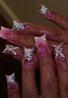 a woman's hand with pink and white nail designs on her nails, including flowers