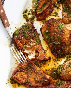 a white plate topped with meat covered in herbs