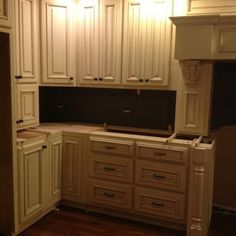 an empty kitchen with white cabinets and wood floors