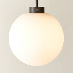 a white ball light hanging from a black metal hook on a gray wall with an orange cord