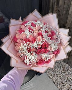 a bouquet of pink roses and baby's breath is being held by a woman