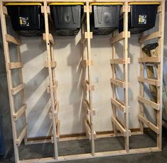 three empty bins are lined up against the wall in a storage room with wooden shelves