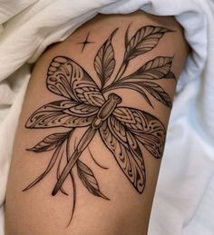 a dragonfly tattoo on the back of a woman's thigh