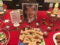 a table topped with cookies and desserts on top of a red cloth covered table