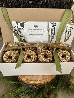 an open box filled with donuts sitting on top of a tree stump