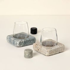 three rocks and two wine glasses on a white surface