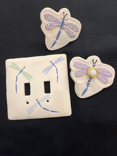 three dragonfly switch plates are shown on a black surface with white and blue accents