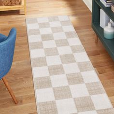 a white and beige checkered rug on the floor in a living room next to a blue chair