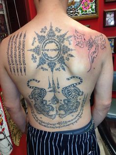 the back of a man with tattoos on his upper and lower part of his body