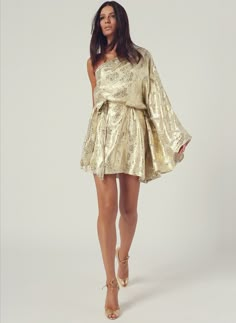 Look 13 One Sleeve Belted Mini Dress Gold Shimmer | Melissa Odabash US Luxury Gold Cocktail Dresses, Luxury Gold Mini Dress For Gala, Luxury Gold Dress For Formal Occasions, Glamorous Gold Mini Dress, Luxury Gold Dresses For Party, Luxury Gold Dress For Night Out, Festive Gold Dress For Night Out, Glamorous Gold Holiday Dresses, Gold Glamorous Holiday Dresses