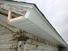 an old wooden house with a white roof and gutter attached to it's side