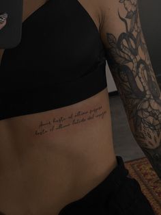 a woman's stomach with a tattoo on her left side and words written in the upper half