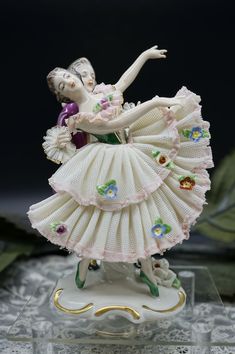 a figurine of a ballerina in white and pink dress with flowers on her skirt