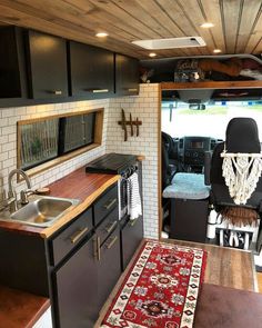 the interior of a camper with wood flooring and black cabinets, including a sink