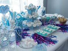 a table topped with lots of desserts next to a bottle of water and glasses