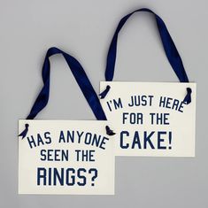 two signs that say i'm just here for the cake and has anyone seen the rings?