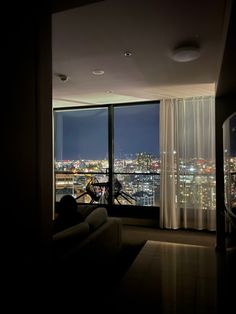 a living room filled with furniture and a large window overlooking the city lights at night