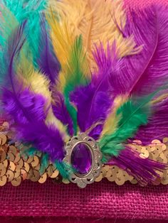 a purple, green and yellow feather headband with a ring on top of coins