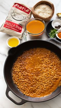 a pan filled with food sitting on top of a counter next to spices and seasonings