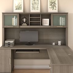 a desk with a computer on it in front of two framed pictures and bookshelves