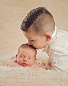 two babies are cuddling and kissing each other on a white furnishing blanket