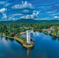 an aerial view of a white tower in the middle of a lake surrounded by trees