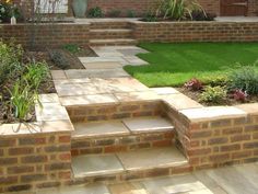 an outdoor garden with steps leading up to the front door and grass in the back yard