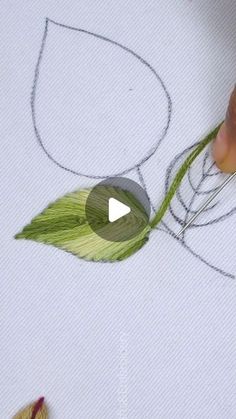 someone is drawing something with colored pencils on paper and using scissors to draw the leaves